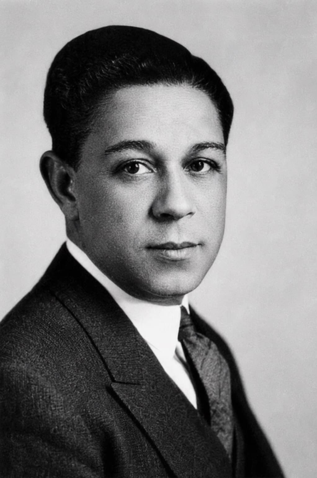 Black-and-white studio portrait of Dr. Simmons C. Hamilton in a suit and dark tie, smiling slightly